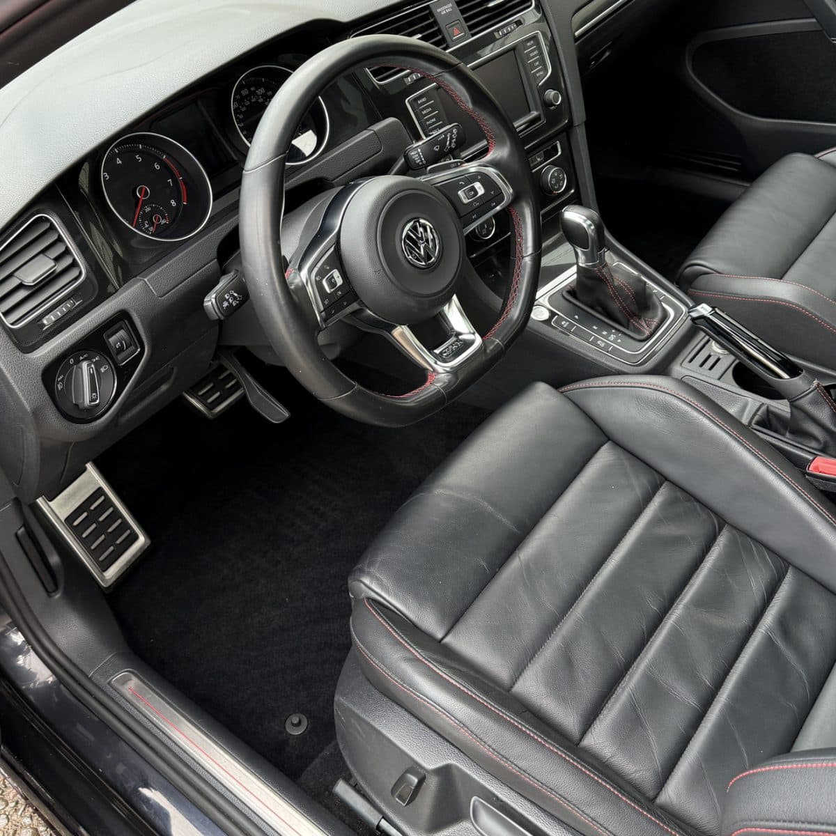 The same Volkswagen GTI interior after detailing, with a clean floor and conditioned leather seats