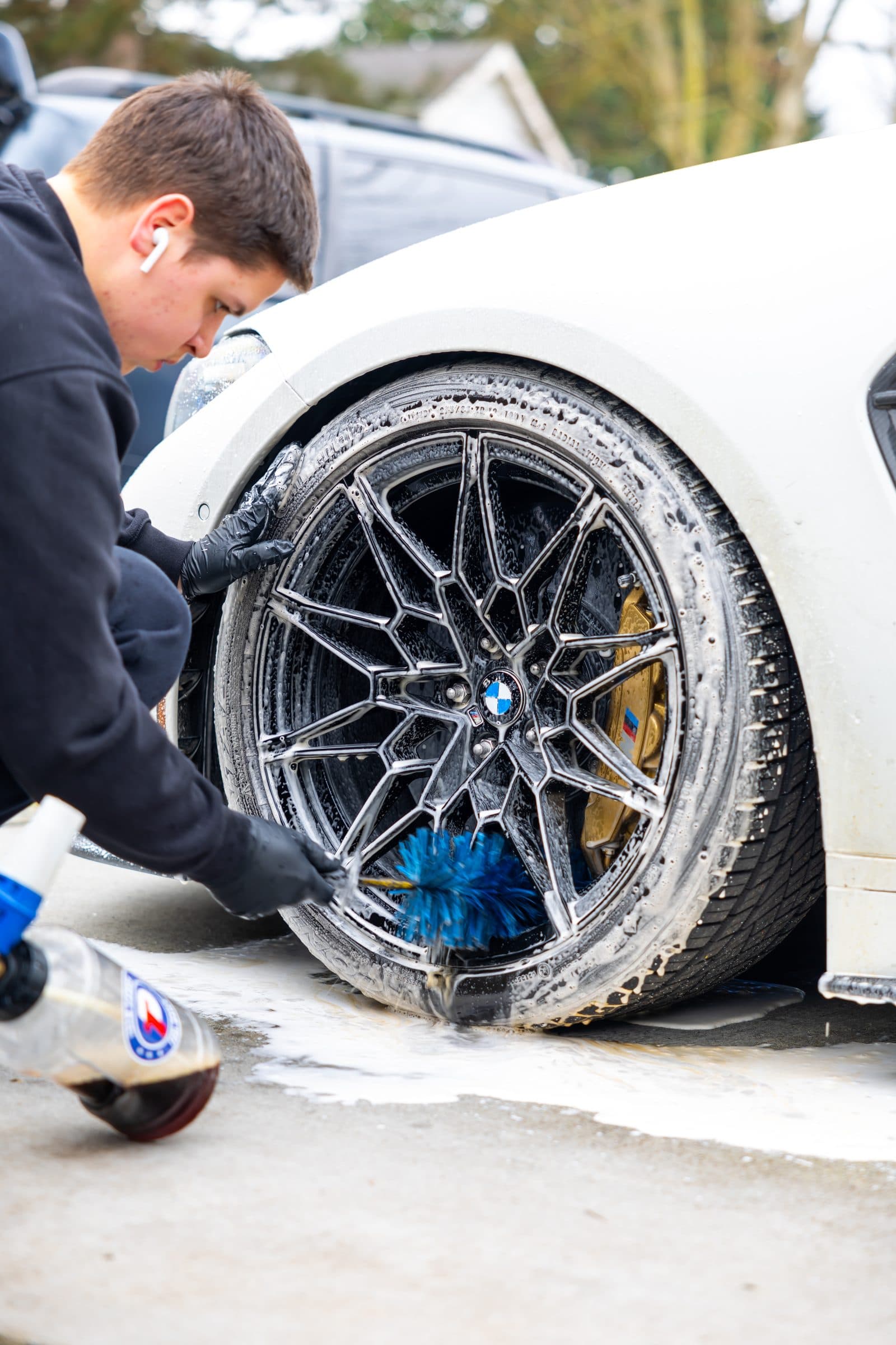 Refined Auto Detailing cleaning a BMW wheel with a brush during a mobile detail